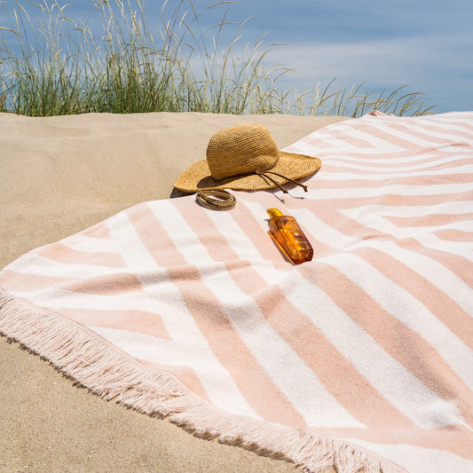 Strandhanddoek Zand met subtiele streepjesmotief op een zonnig strand, ideaal voor zonnebaden of afdrogen na het zwemmen.